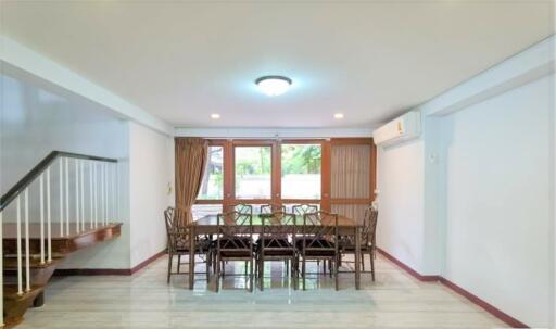 Dining room with a large dining table and chairs, near windows with curtains