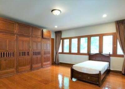 Spacious bedroom with wooden furnishings and ample natural light.