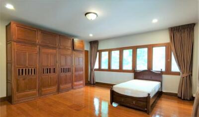 Spacious bedroom with wooden furnishings and ample natural light.