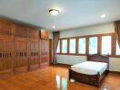 Spacious bedroom with wooden furnishings and ample natural light.