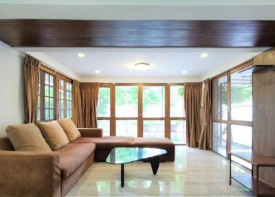 Spacious living room with large windows, brown sofa, and modern coffee table