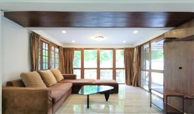 Spacious living room with large windows, brown sofa, and modern coffee table