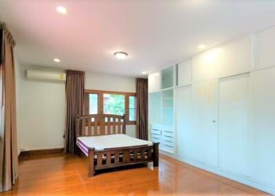 Spacious bedroom with wooden flooring, a large bed, built-in wardrobe, and windows with curtains