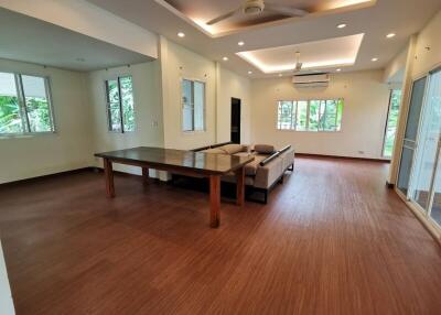 Spacious living room with wooden flooring, modern lighting, and large windows