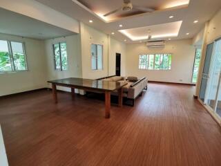 Spacious living room with wooden flooring, modern lighting, and large windows