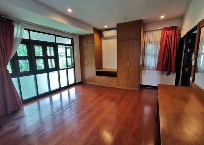 Spacious bedroom with large windows, wooden flooring, and built-in wardrobes