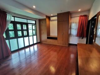 Spacious bedroom with large windows, wooden flooring, and built-in wardrobes