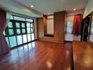 Spacious bedroom with large windows, wooden flooring, and built-in wardrobes