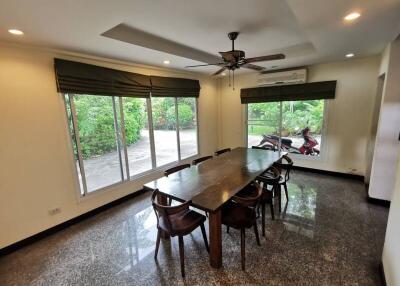 Spacious dining room with large table and chairs, featuring a ceiling fan and large windows offering plenty of natural light