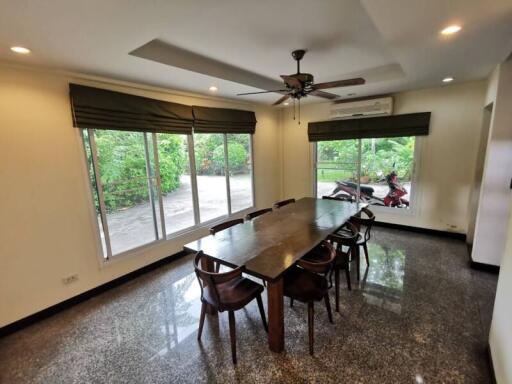 Spacious dining room with large table and chairs, featuring a ceiling fan and large windows offering plenty of natural light