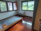 Bedroom with large windows, bed frame, and wooden flooring