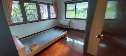 Bedroom with large windows, bed frame, and wooden flooring