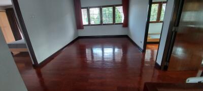 Spacious bedroom with wooden flooring and large windows