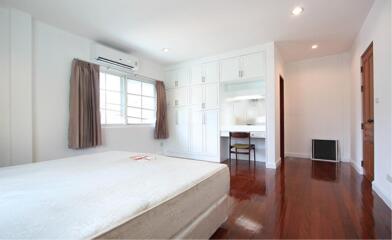 Bedroom with wooden floor, white bed, built-in cabinets, and a study nook