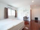 Bedroom with wooden floor, white bed, built-in cabinets, and a study nook