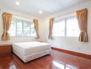 Bright bedroom with wooden flooring and large windows