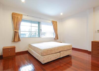 Bright bedroom with a large window, bed, nightstands, and wooden flooring