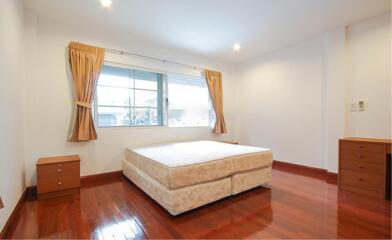 Bright bedroom with a large window, bed, nightstands, and wooden flooring