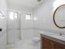 Modern bathroom with a glass-enclosed shower, vanity with mirror, and toilet