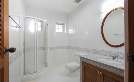 Modern bathroom with a glass-enclosed shower, vanity with mirror, and toilet