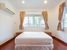 Cozy bedroom with a bed, windows, and wooden flooring