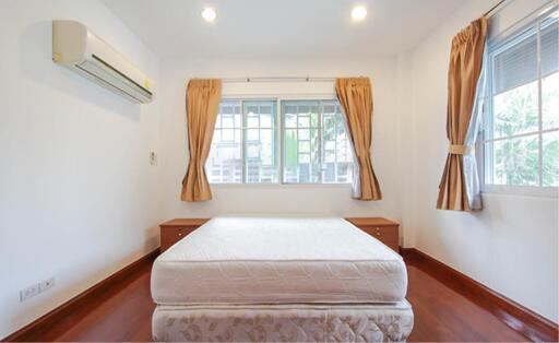 Cozy bedroom with a bed, windows, and wooden flooring