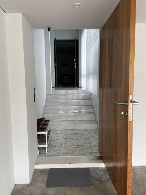 entrance hallway with open wooden door and steps leading to interior