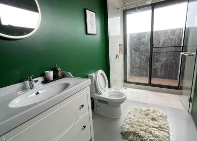 Modern bathroom with green accent wall, white vanity, and glass shower enclosure