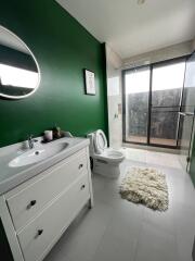 Modern bathroom with green accent wall, white vanity, and glass shower enclosure