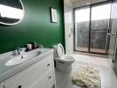 Modern bathroom with green accent wall, white vanity, and glass shower enclosure