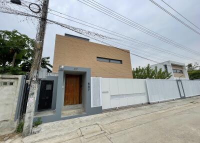 Modern house exterior with wooden door and white fence