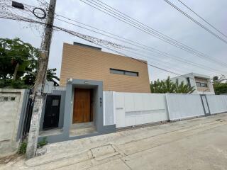 Modern house exterior with wooden door and white fence