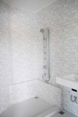 Modern bathroom with white brick-style tiles and a sleek shower panel