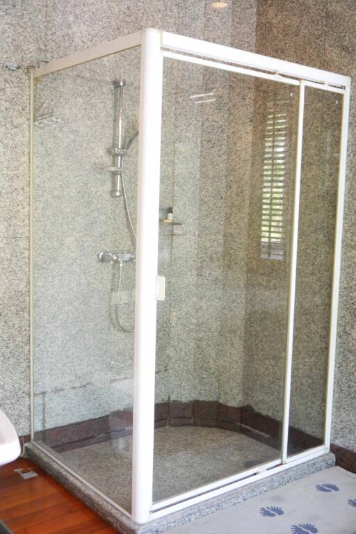 Modern glass shower enclosure in a bathroom with grey marble walls