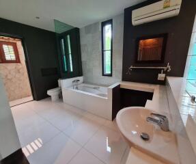 Modern bathroom with bathtub, sink, and air conditioning unit