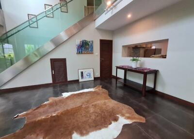 Modern living room with a glass staircase, artwork, and a cowhide rug