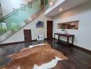 Modern living room with a glass staircase, artwork, and a cowhide rug