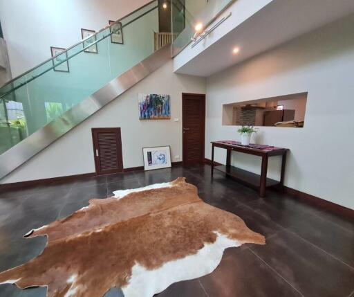 Modern living room with a glass staircase, artwork, and a cowhide rug