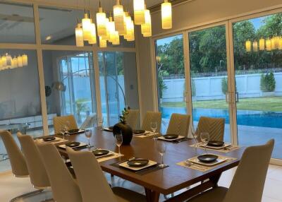 Modern dining room with contemporary light fixtures and large windows overlooking a pool