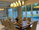 Modern dining room with contemporary light fixtures and large windows overlooking a pool