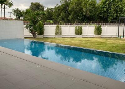 A spacious backyard with a swimming pool under a cloudy sky