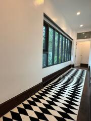 Long hallway with patterned floor rug and large windows