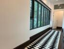 Long hallway with patterned floor rug and large windows