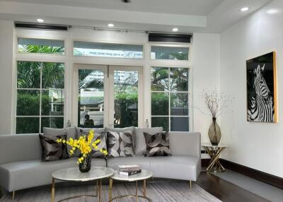 Modern living room with large windows, gray couch, and coffee tables