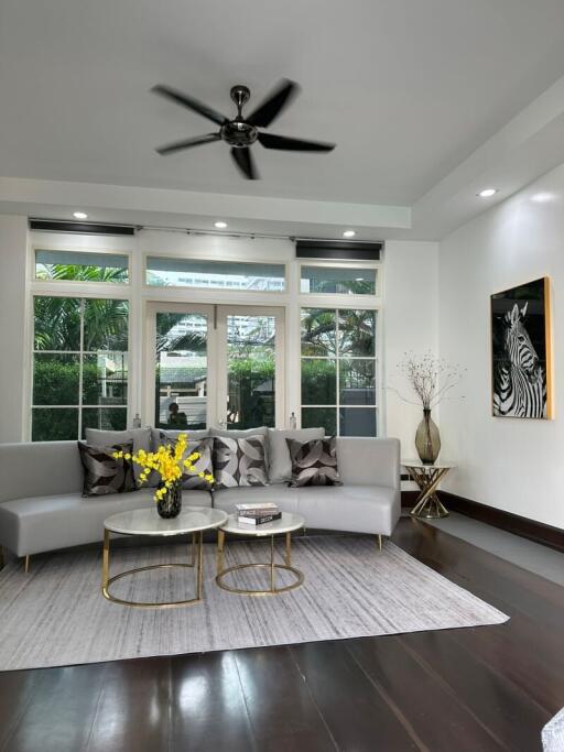 Modern living room with large windows, gray couch, and coffee tables