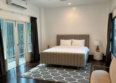 Modern bedroom with a large bed, ceiling fan, and natural light