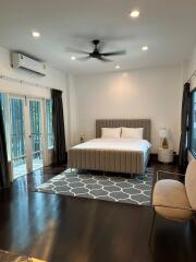 Modern bedroom with a large bed, ceiling fan, and natural light