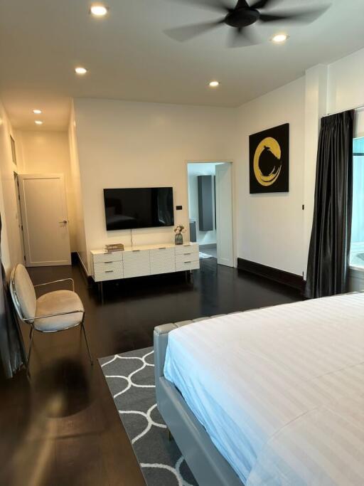 Modern bedroom with wall-mounted TV and dark hardwood flooring