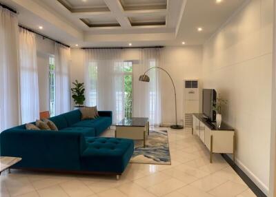 Spacious and modern living room with blue sectional sofa, large windows, and contemporary decor