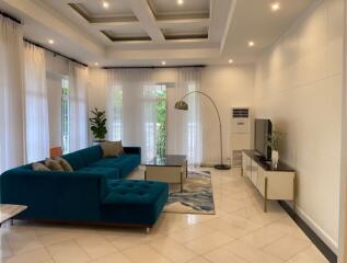 Spacious and modern living room with blue sectional sofa, large windows, and contemporary decor